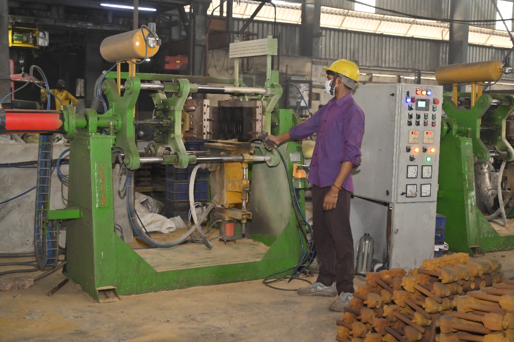 Technician operating green horizontal moulding sand core shooter